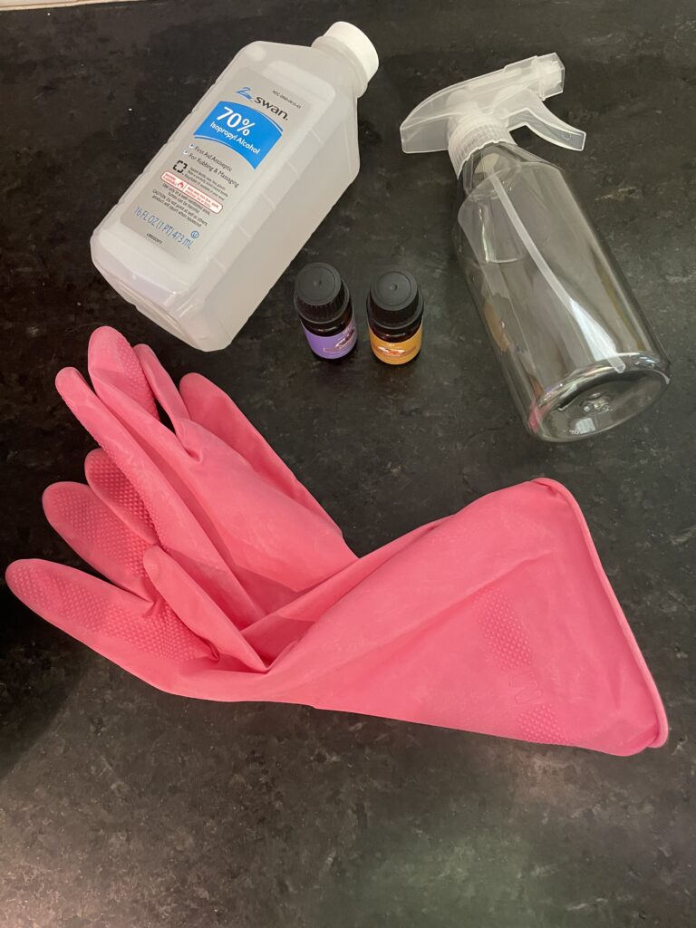 DIY disinfectant materials including spray bottle, rubber gloves, essential oils, and Isopropyl alcohol.
